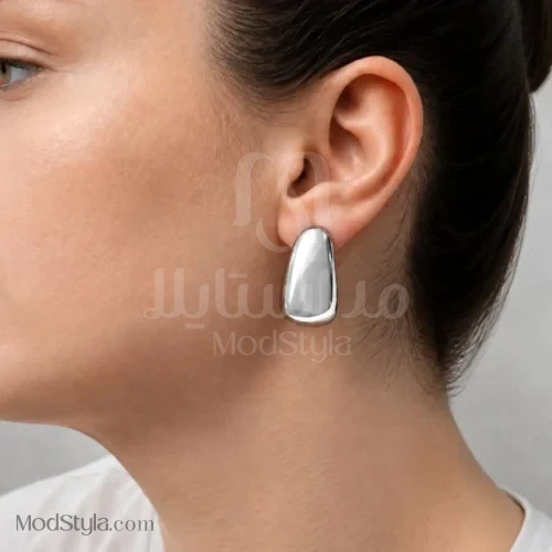 نمای نزدیک گوشواره هندسی زنانه نقره‌ای با سطح براق